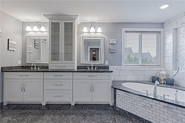 bathroom with a sink, a bath, and double vanity