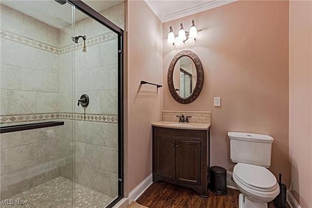 bathroom featuring crown molding, toilet, a shower stall, wood finished floors, and baseboards