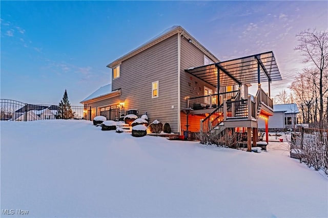 snow covered property with a garage, fence, and stairs