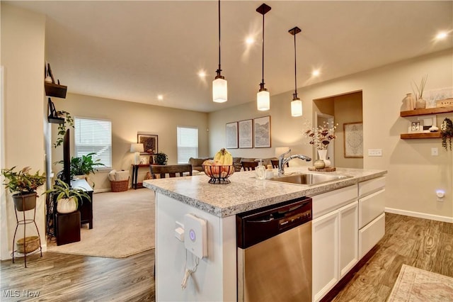 kitchen featuring open floor plan, dishwasher, wood finished floors, white cabinets, and a sink