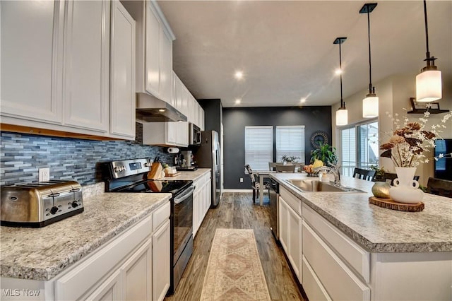 kitchen featuring a sink, backsplash, exhaust hood, stainless steel appliances, and a kitchen island with sink