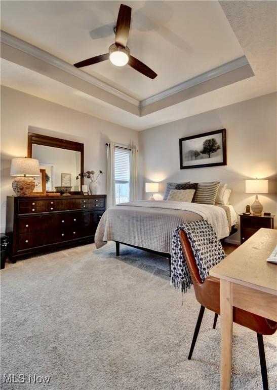 bedroom with a raised ceiling, carpet, ceiling fan, and crown molding