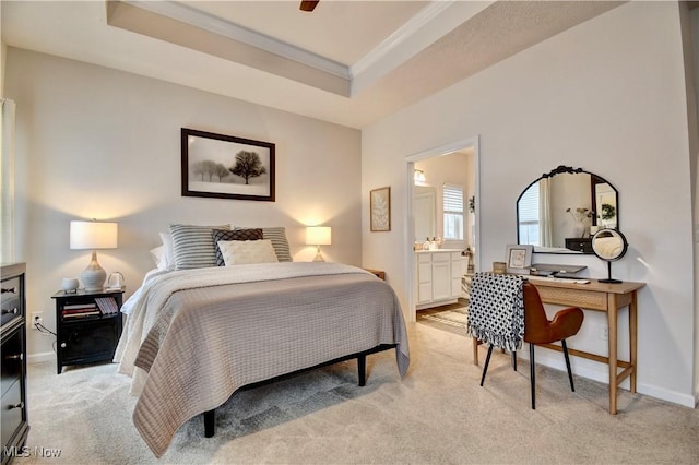 bedroom with a raised ceiling, ornamental molding, ensuite bath, baseboards, and light colored carpet