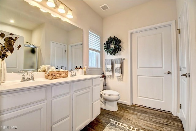 full bathroom with double vanity, visible vents, wood finished floors, and a sink