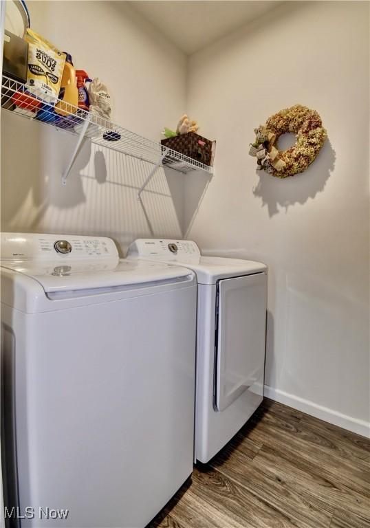 washroom featuring washer and clothes dryer, laundry area, baseboards, and wood finished floors