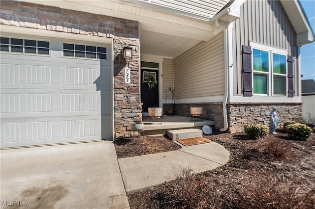 view of exterior entry with board and batten siding, a garage, and stone siding