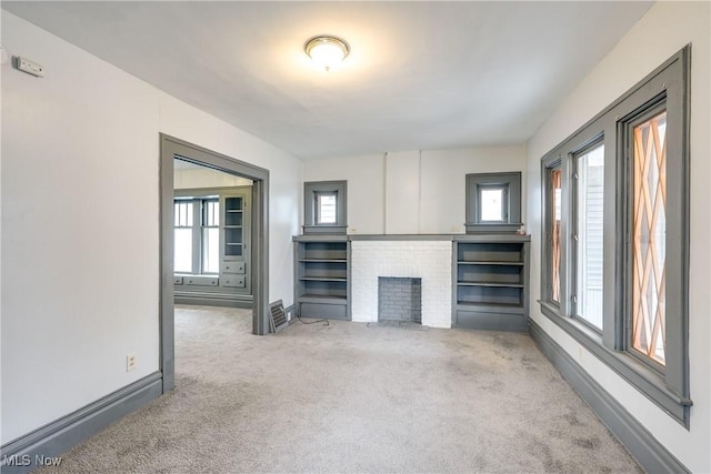 unfurnished living room featuring carpet floors, a fireplace, and baseboards