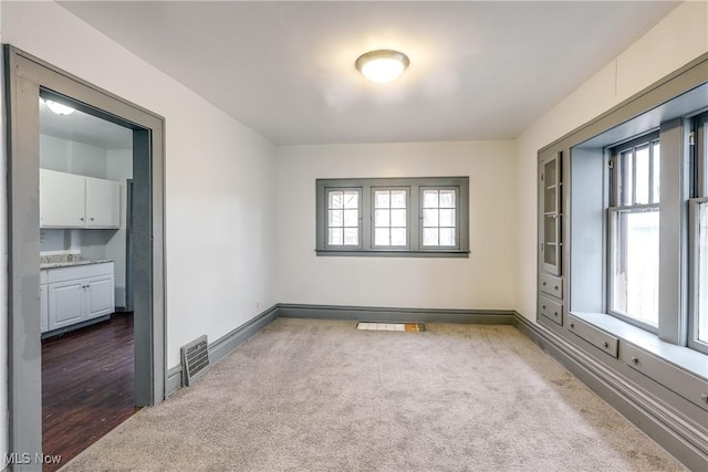 empty room featuring carpet, visible vents, and baseboards