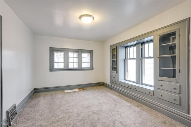 spare room featuring a wealth of natural light, visible vents, baseboards, and carpet flooring