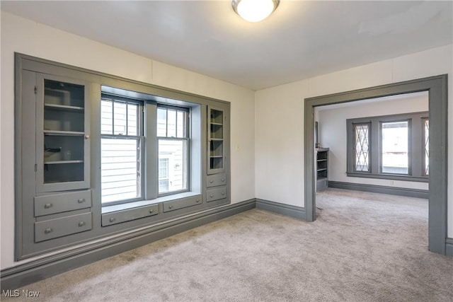 spare room with carpet floors, baseboards, and a wealth of natural light