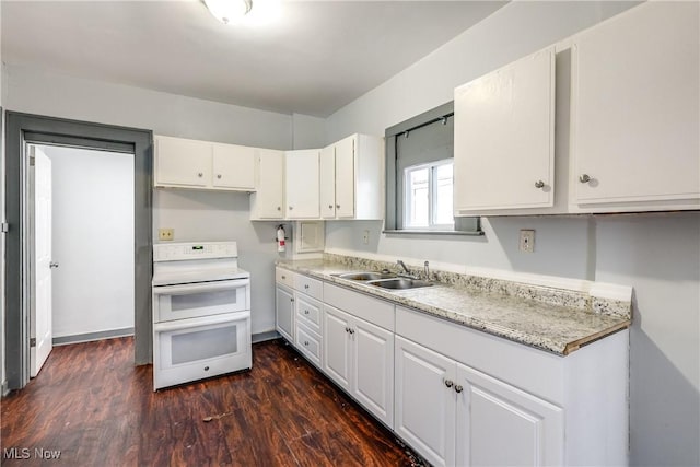 kitchen with a sink, baseboards, white cabinets, double oven range, and dark wood-style floors