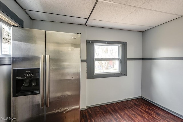 kitchen with a paneled ceiling, dark wood-style flooring, stainless steel refrigerator with ice dispenser, and baseboards