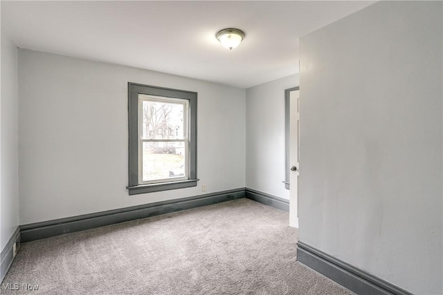 carpeted empty room featuring a baseboard radiator and baseboards