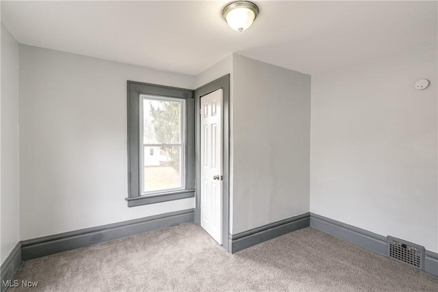 carpeted empty room with visible vents and baseboards