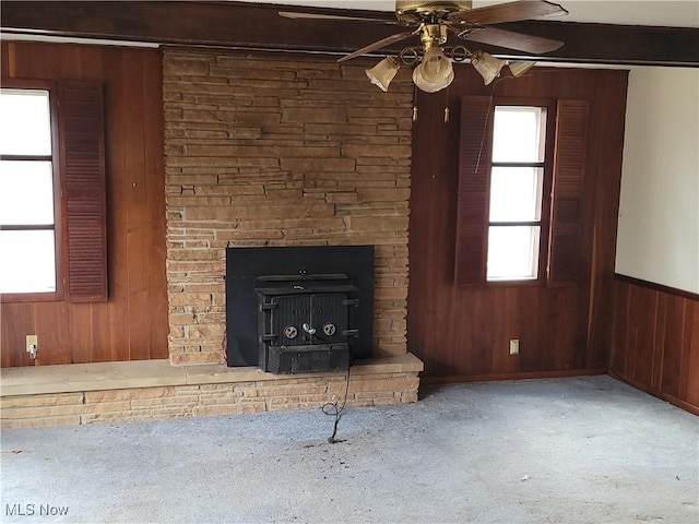 unfurnished living room with ceiling fan, carpet floors, wainscoting, and wooden walls