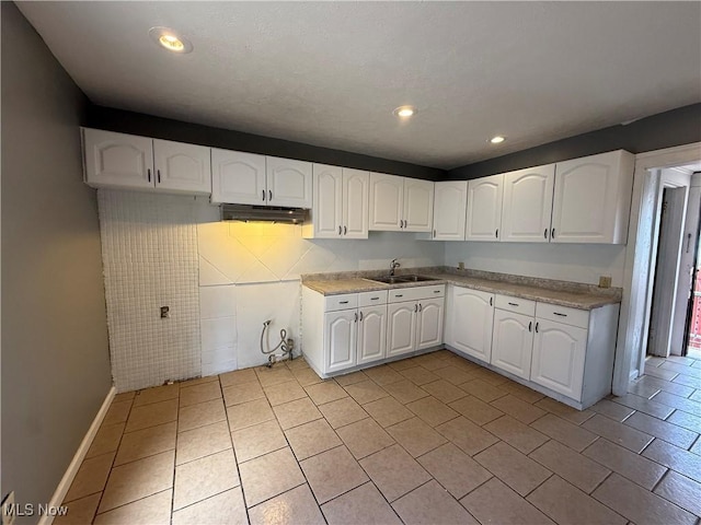 kitchen featuring white cabinetry, a sink, and under cabinet range hood