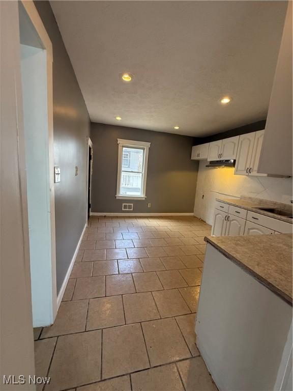 kitchen with recessed lighting, a sink, white cabinetry, and baseboards