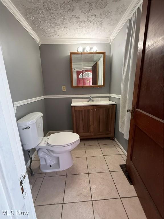 half bathroom with a textured ceiling, ornamental molding, tile patterned flooring, and toilet