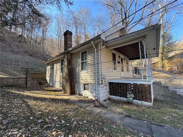 view of property exterior featuring covered porch and a chimney