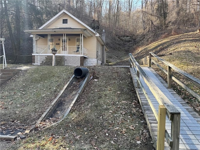 view of side of home featuring a porch and fence