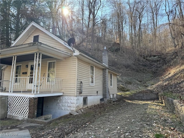 view of side of property with covered porch and a chimney