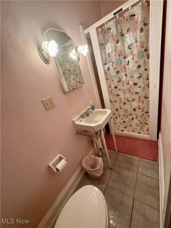 bathroom with baseboards, a sink, a shower stall, and toilet