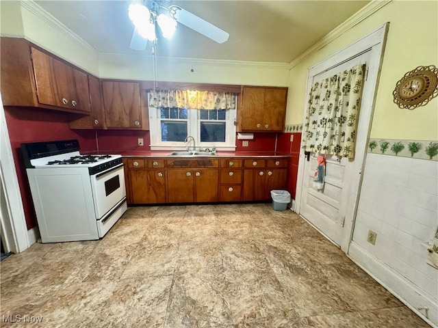 kitchen with a sink, a ceiling fan, white range with gas cooktop, ornamental molding, and brown cabinets