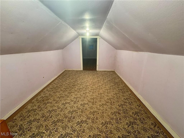 bonus room featuring lofted ceiling, a textured ceiling, carpet, and baseboards