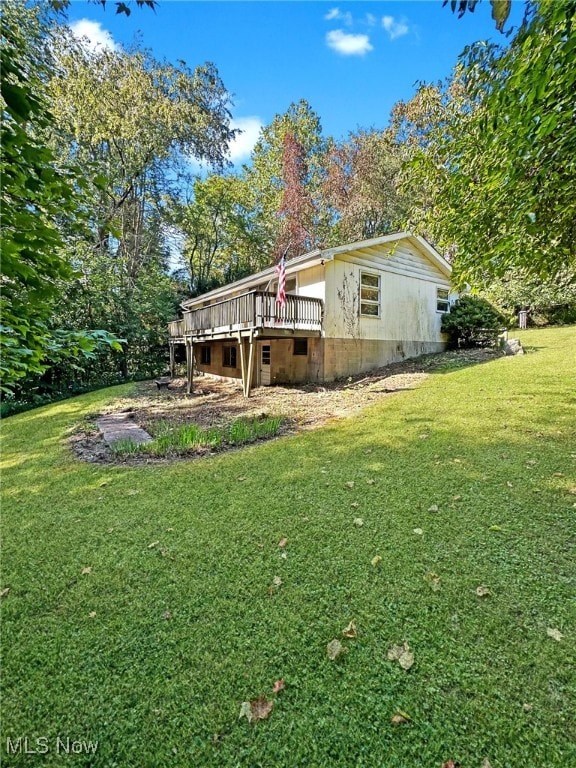 view of side of property featuring a deck, crawl space, and a lawn