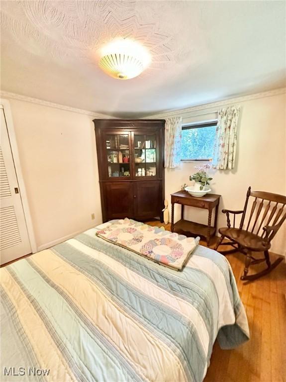 bedroom featuring a textured ceiling, wood finished floors, and crown molding