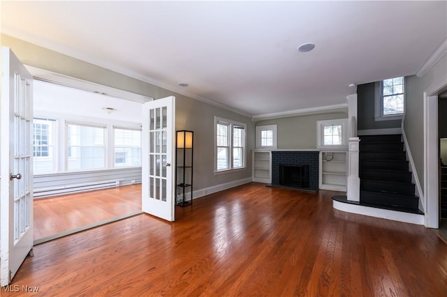 unfurnished living room featuring stairs, ornamental molding, a brick fireplace, hardwood / wood-style floors, and plenty of natural light