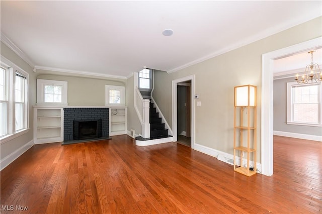 unfurnished living room featuring a fireplace, crown molding, stairway, and wood finished floors