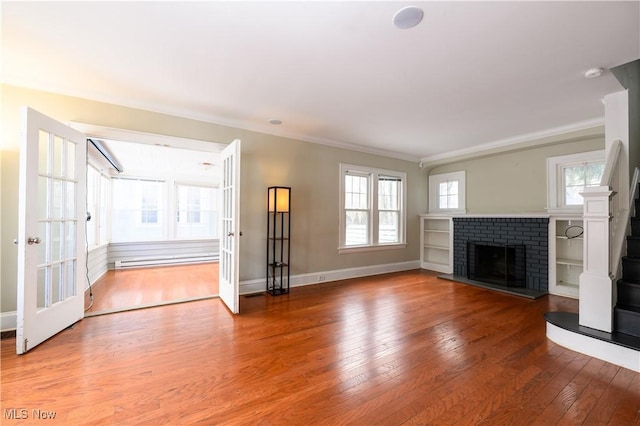 unfurnished living room with crown molding, a fireplace, baseboards, and hardwood / wood-style flooring