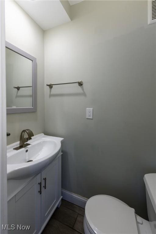 bathroom featuring visible vents, toilet, vanity, baseboards, and tile patterned floors