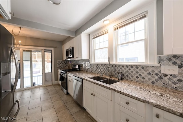 kitchen with light tile patterned floors, white cabinets, a sink, stainless steel appliances, and backsplash