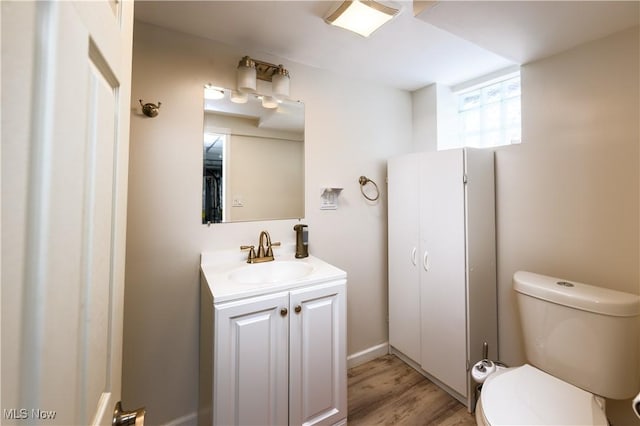 half bathroom with vanity, toilet, and wood finished floors