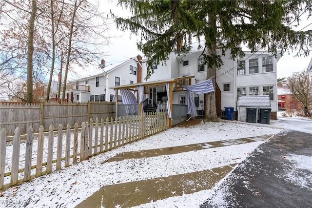 snow covered rear of property with a fenced front yard