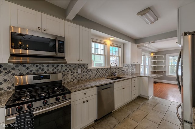 kitchen featuring tasteful backsplash, white cabinets, light stone counters, stainless steel appliances, and a sink