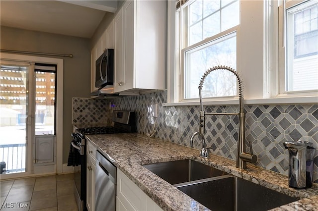 kitchen featuring appliances with stainless steel finishes, white cabinets, a sink, and decorative backsplash