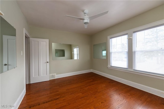 spare room featuring a ceiling fan, baseboards, visible vents, and dark wood-type flooring