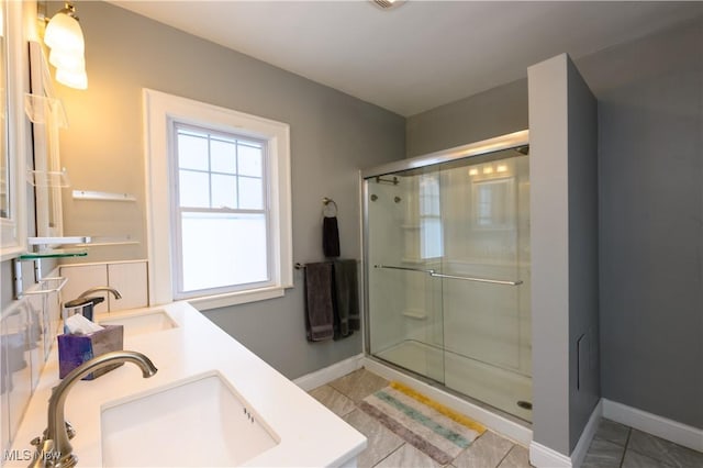 bathroom with double vanity, a sink, a shower stall, and tile patterned floors