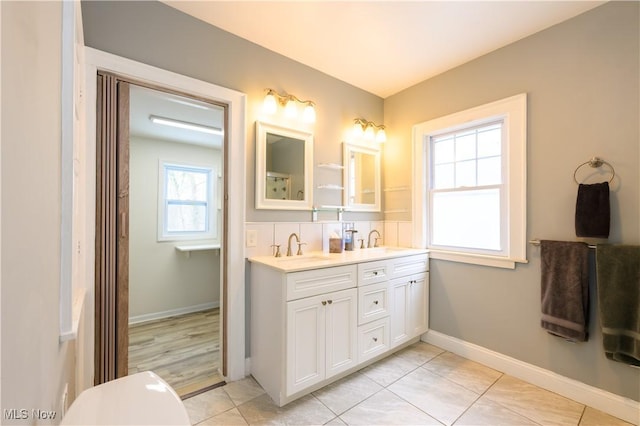 bathroom featuring tile patterned flooring, a sink, baseboards, and double vanity