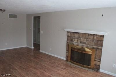 unfurnished living room with baseboards, a fireplace, visible vents, and wood finished floors