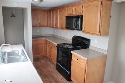 kitchen featuring dark wood finished floors, light countertops, a sink, and black appliances