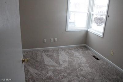 carpeted spare room featuring visible vents and baseboards