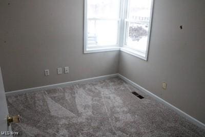 carpeted spare room featuring visible vents and baseboards