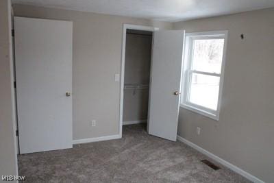 unfurnished bedroom featuring multiple windows, baseboards, a closet, and carpet flooring