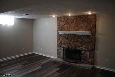 below grade area with a textured ceiling, a fireplace, wood finished floors, and baseboards