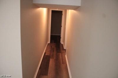 hall with dark wood-style flooring and baseboards