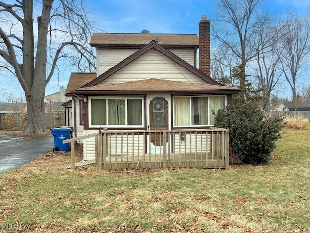 view of front of property featuring aphalt driveway, a chimney, and a front lawn